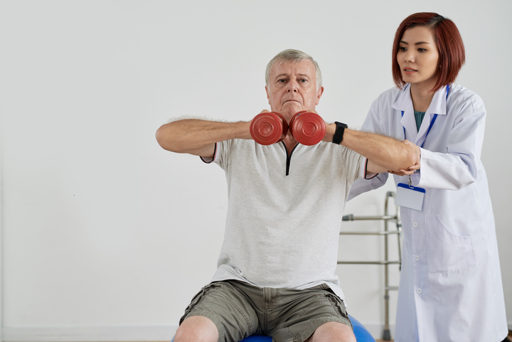 aged man exercising with dumbbells in the hospital